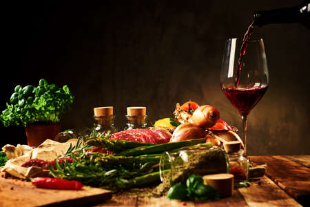 Fresh raw meat with herbs, glass of red wine and vegetables.の写真素材