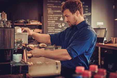 Handsome barista preparing cup of coffee for customer in coffee shop.の写真素材
