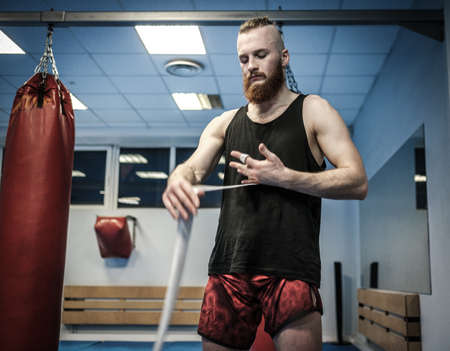 Fighter preparing for training, wrapping hands with boxing wrapsの写真素材