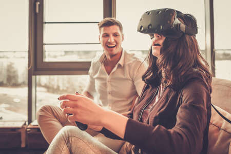 Cheerful couple having fun with VR in home interior
