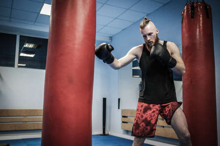Fighter training with punching bag at gymの写真素材