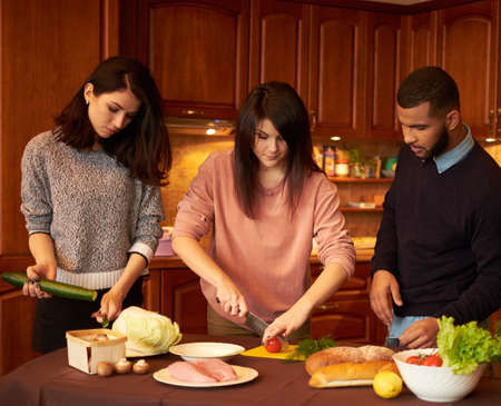 Group of multi ethnic young friends in kitchen prepare for partyの写真素材