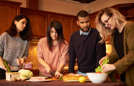 Group of multi ethnic young friends in kitchen prepare for partyの写真素材