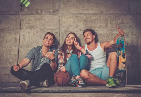 Cheerful friends with with skateboard taking selfie outdoorsの写真素材