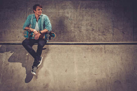 Handsome young man with skateboard outdoorsの写真素材