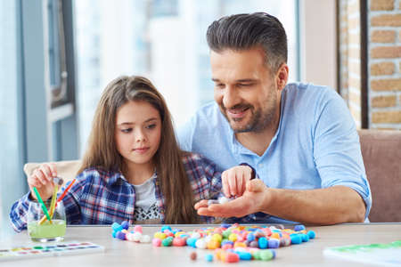 Beautiful little girl with her father playing with colored set for creativityの写真素材