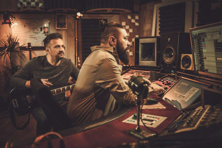 Sound engineer and guitarist recording song in boutique recording studioの写真素材