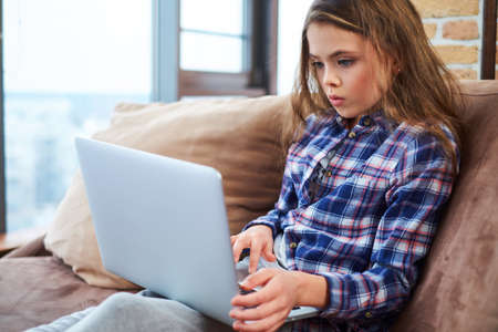 Pretty little girl using notebook on a couchの写真素材
