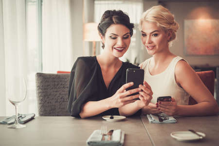 Two elegant ladies taking selfie in restaurant