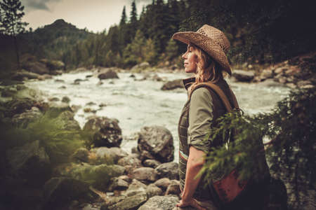 Beautiful woman hiker near wild mountain riverの写真素材