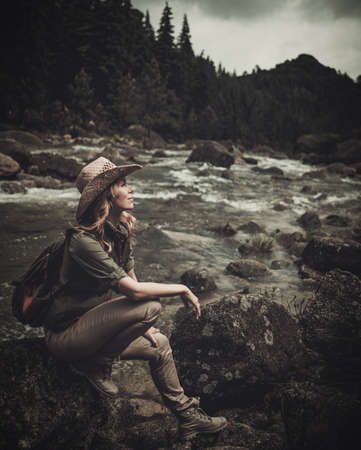 Beautiful woman hiker near wild mountain riverの写真素材
