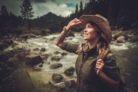 Beautiful woman hiker near wild mountain riverの写真素材