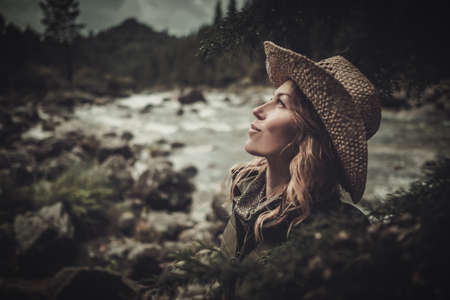 Beautiful woman hiker near wild mountain riverの写真素材