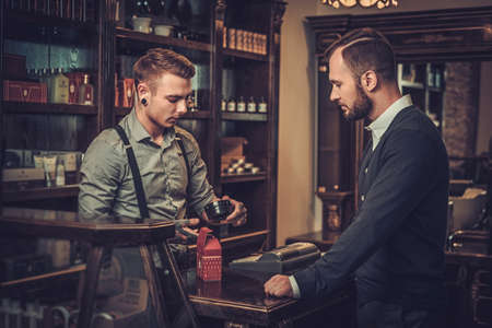 Confident man buying hair care accessories in barber shopの写真素材