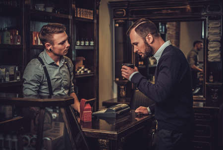 Confident man buying hair care accessories in barber shopの写真素材