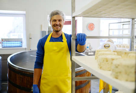 Handsome cheesemaker making curd cheese in his factoryの写真素材