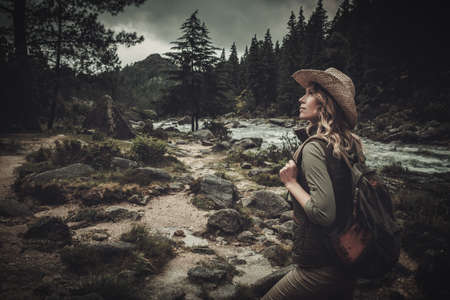 Beautiful woman hiker near wild mountain river.の写真素材