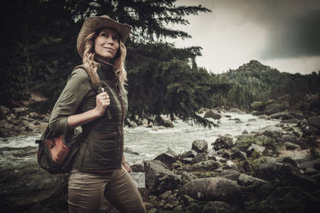 Beautiful woman hiker near wild mountain river.の写真素材