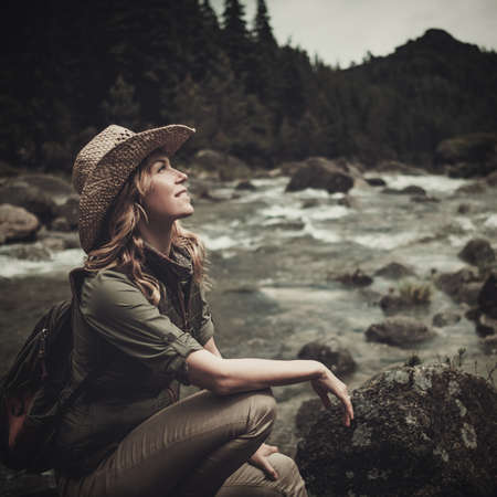 Beautiful woman hiker near wild mountain river.の写真素材