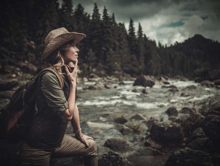 Beautiful woman hiker near wild mountain river.の写真素材