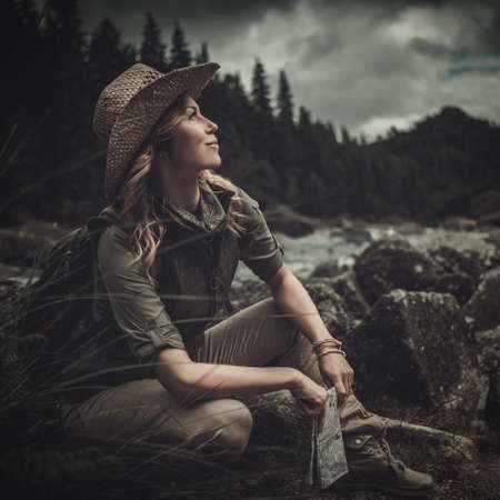 Beautiful woman hiker near wild mountain river.の写真素材