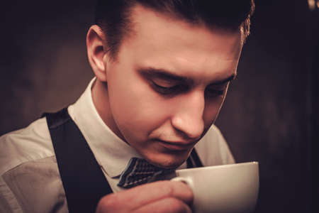Sharp dressed man wearing waistcoat with a cup of coffeeの写真素材