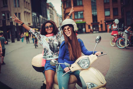 Multi ethnic girls on a scooter in european cityの写真素材