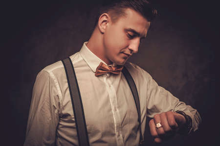 Sharp dressed man wearing bow tie looking at wristwatchの写真素材
