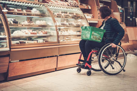 Disabled woman in a wheelchair in a grocery storeの写真素材