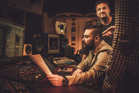 Sound engineer and musicians working in boutique recording studio.