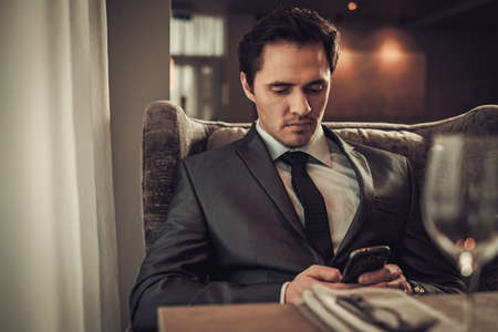 Confident man with smart phone in restaurant.