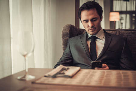 Confident man with smart phone in restaurant.の写真素材