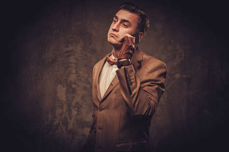 Sharp dressed man with mobile phone wearing jacket and bow tieの写真素材