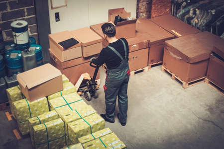 Storekeeper working with pallet truck in a warehouseの写真素材