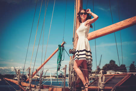 Stylish wealthy woman on a luxury wooden regattaの写真素材