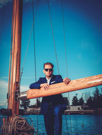 Stylish wealthy man on a luxury wooden regattaの写真素材