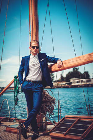 Stylish wealthy man on a luxury wooden regattaの写真素材