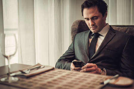 Confident man with smart phone in restaurant.の写真素材