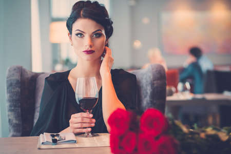 Elegant lady with red roses in restaurantの写真素材