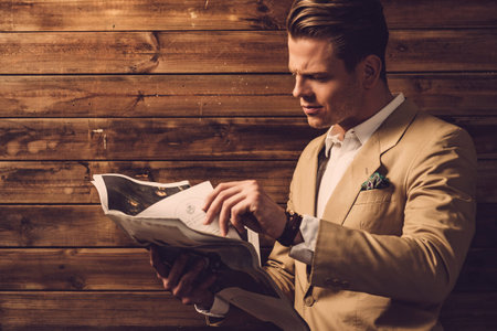 Stylish man with newspaper in rural cottage interiorの写真素材