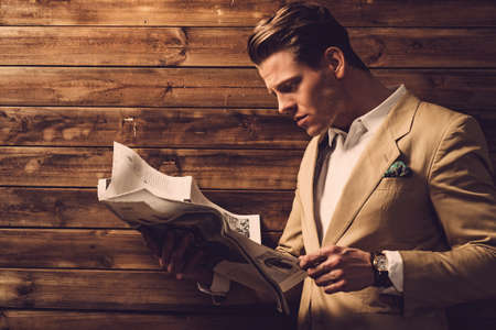 Stylish man with newspaper in rural cottage interiorの写真素材
