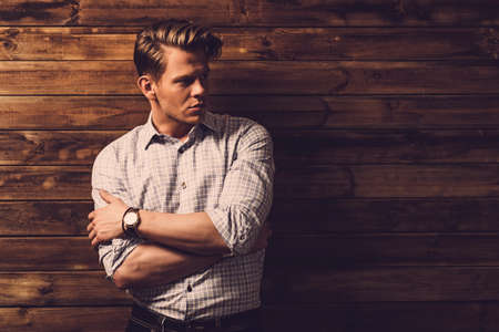 Handsome man wearing checkered shirt in wooden rural house interiorの写真素材