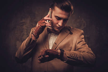 Sharp dressed man with mobile phone wearing jacket and bow tieの写真素材