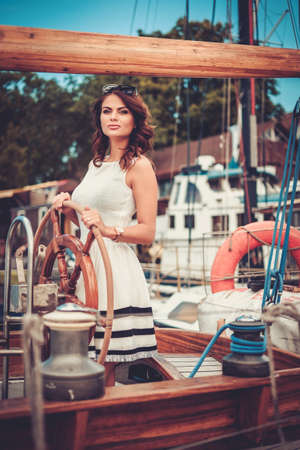 Stylish wealthy woman on a luxury wooden regattaの写真素材