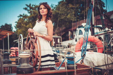 Stylish wealthy woman on a luxury wooden regattaの写真素材