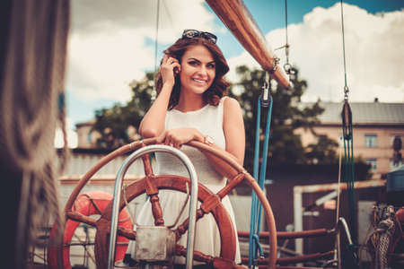 Stylish wealthy woman on a luxury wooden regattaの写真素材