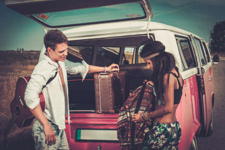Multi-ethnic hippie couple with guitar packing luggage for a road tripの写真素材