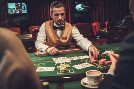 Croupier behind gambling table in a casinoの写真素材