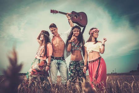 Multinational hippie friends with guitar in a wheat fieldの写真素材