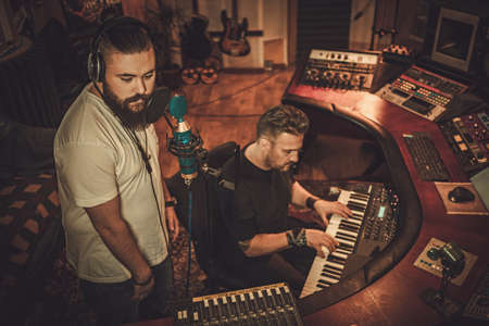 Musicians recording vocal and keyboards in boutique recording studio.の写真素材